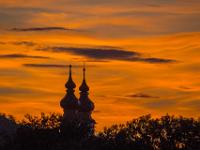 Wolken UFO's am glühenden Himmel hinter Kirchtürmen